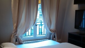 Una camera da letto con un letto grande, una finestra con tende e una televisione su un mobile.