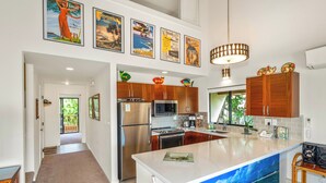 A modern kitchen with wooden cabinets, stainless steel appliances, and a large island. - Maui Kamaole K-207 Recently Remodeled, Views, Pools, Hot Tub, A/C, W/D (Kihei)