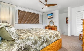 A bedroom with a bed, a ceiling fan, a window with blinds, a dresser, and a mirror.