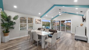 A modern dining area with a white table and chairs, a ceiling fan, and a view of the outside.