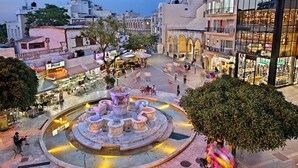A public square with a central fountain, surrounded by cafes and shops. - City Center Apartment Project 3 by Cretan Houses (Heraklion)