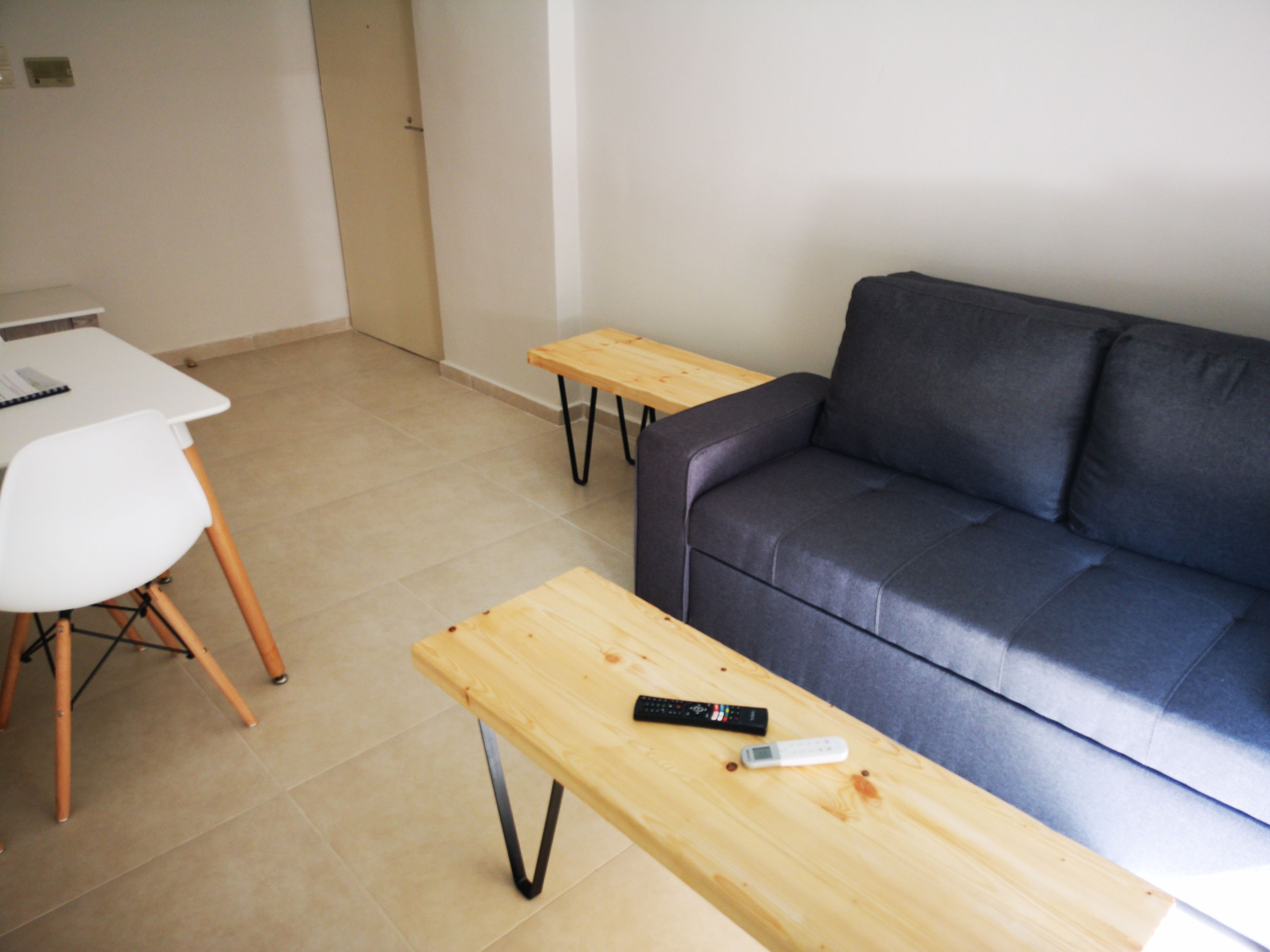 A living room with a grey sofa, a white chair, and two wooden tables.