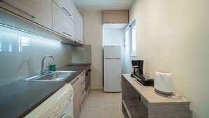 A compact kitchen with a washing machine, a coffee maker, and a refrigerator. - City Center Apartment Project 3 by Cretan Houses (Heraklion)