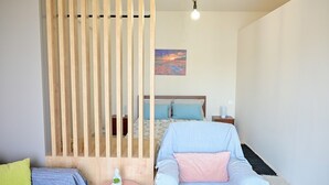 Ein Schlafzimmer mit einem Bett, einem Sessel, einem kleinen Tisch und einer Holzwand.