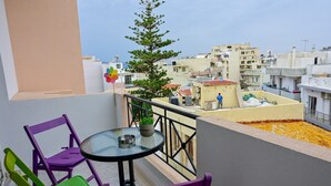 Ein Balkon mit violetten Stühlen, einem kleinen runden Tisch und einem Blumentopf.
