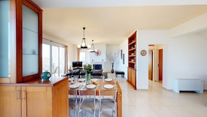 A spacious living area with a dining table set for four, a television, and a fireplace. - Villa Angelika Two-storey House With Pool for 7 (Hersonissos)