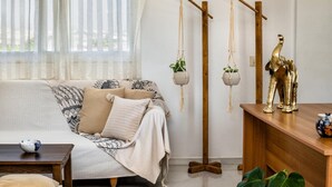 A living room with a sofa, a coffee table, hanging plants, and a decorative elephant statue.
