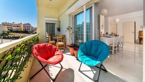 A balcony with two chairs, a dining table, and potted plants.