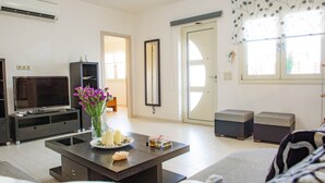 A modern living room with a flat-screen TV, a coffee table with decorative items, and a sofa. - Marie Nicol Apartments 2 (Malevizi)