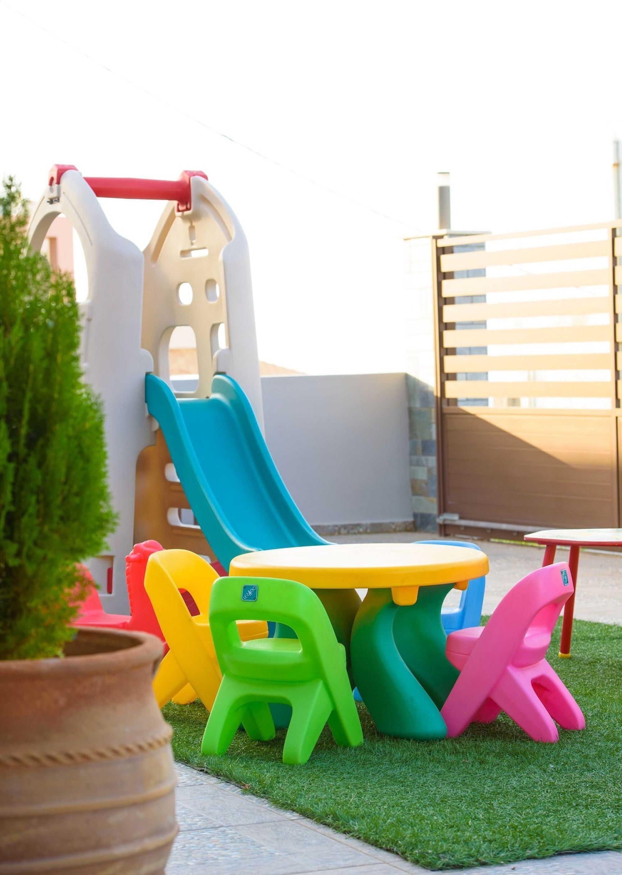A children's play area with a slide, a table, and colorful chairs.