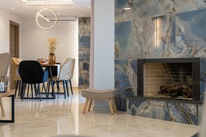 A modern dining area with a marble fireplace, a round light fixture, and a dining table with chairs.