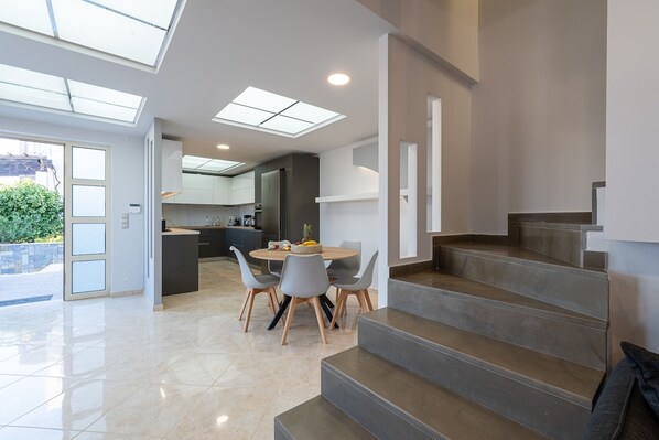 Una cocina moderna con comedor, una escalera y un ventanal que da al exterior.