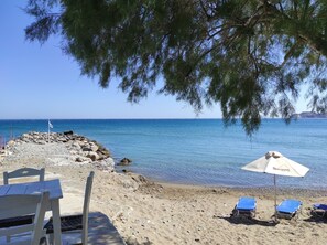 Une plage avec un rivage rocheux, un drapeau et un parasol.