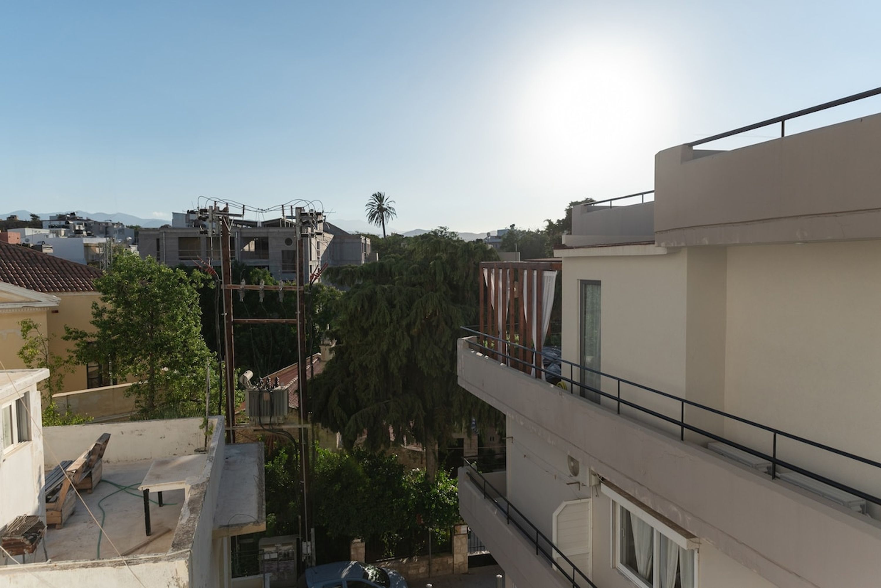A residential building with multiple balconies, a clear sky, and a palm tree in the background.