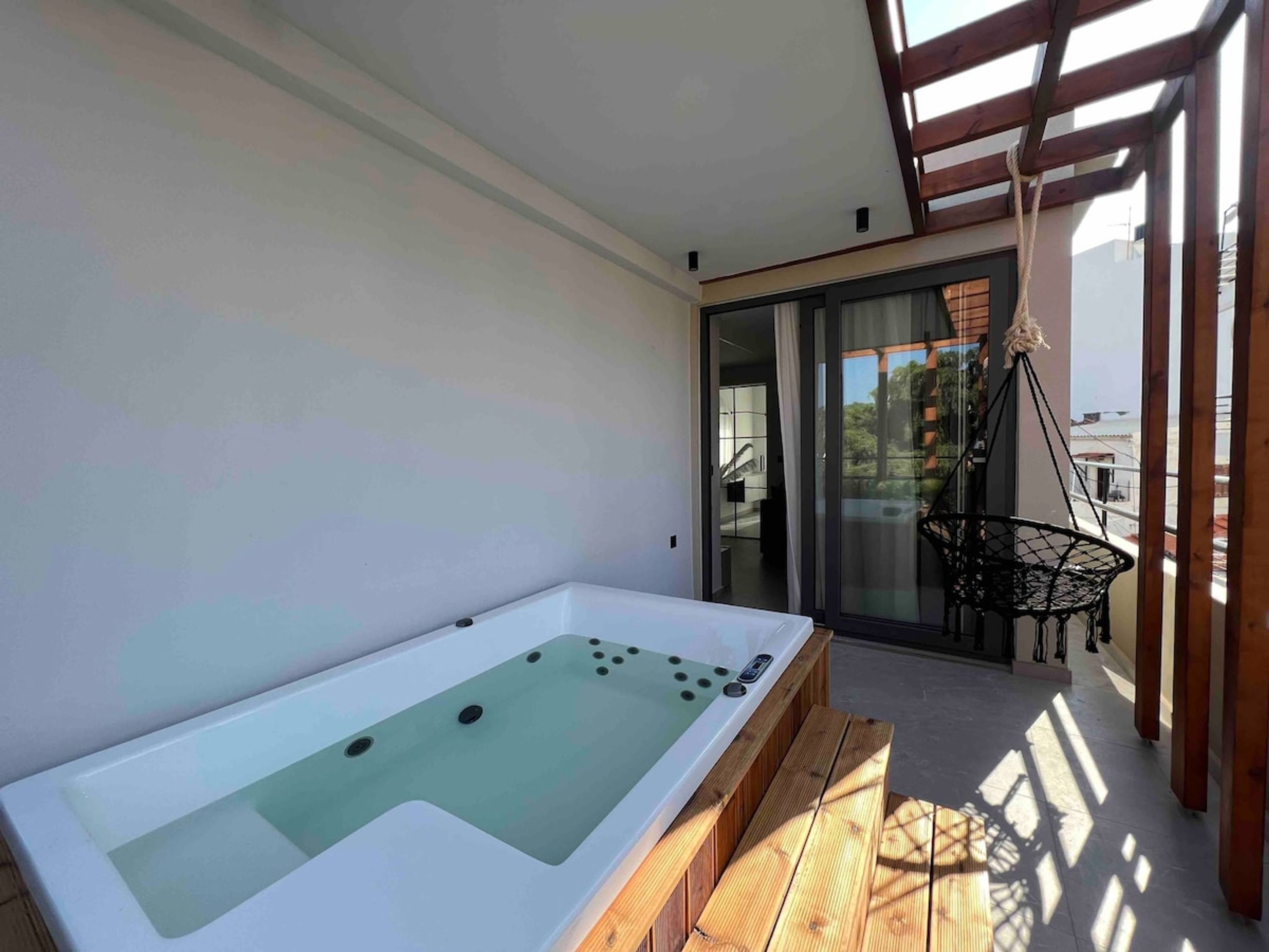 Een moderne spa-ruimte met een jacuzzi, houten terras en uitzicht op de omgeving.