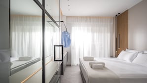 Una habitación de hotel moderna con una cama grande, una mesita de noche, un espejo y un armario.