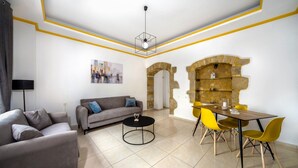 A modern living room with a sofa, coffee table, and dining area with yellow chairs. - Mela s Home Agioi Deka (Gortyna)
