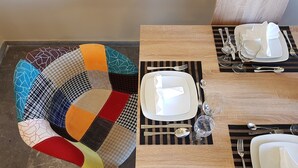 A dining table set with plates, cutlery, and glasses, accompanied by a colorful, patterned chair. - City Center Apartment Project by Cretan Houses (Heraklion)
