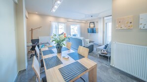A modern meeting room with a wooden table, chairs, a vase with flowers, and a sofa. - City Center Apartment Project by Cretan Houses (Heraklion)