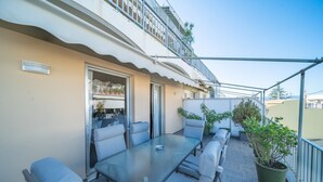 A balcony with a glass table and chairs, potted plants, and a view of the city. - City Center Apartment Project by Cretan Houses (Heraklion)