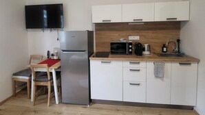 Eine kompakte Küche mit Kühlschrank, Mikrowelle, Wasserkocher und Spüle.