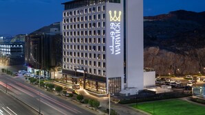 A modern hotel with a prominent sign, multiple floors, and a parking area.
