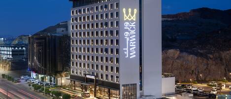 A modern hotel with a prominent sign, multiple floors, and a parking area.