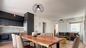 Uma cozinha moderna com armários escuros, uma mesa de jantar de madeira e uma janela grande.