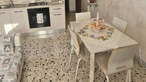 A compact kitchen with modern appliances, a dining table set for two, and a patterned floor.