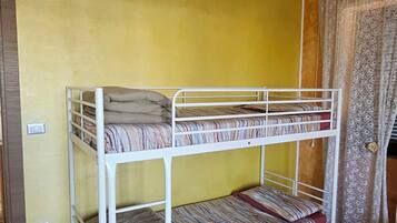 Una cama litera con tres niveles, un colchón estampado y un suelo de baldosas.