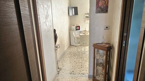 A hallway with a terrazzo floor, a microwave, a television, and a small table with a glass top.