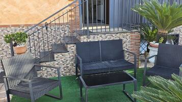 Un patio con mobiliario exterior, una escalera y un muro de ladrillo.