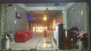 Un espace d’accueil avec un canapé rouge, un fauteuil noir et un comptoir de réception.