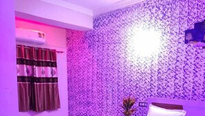 Une chambre à coucher avec un lit, une table de chevet et un mur orné d’un motif floral.