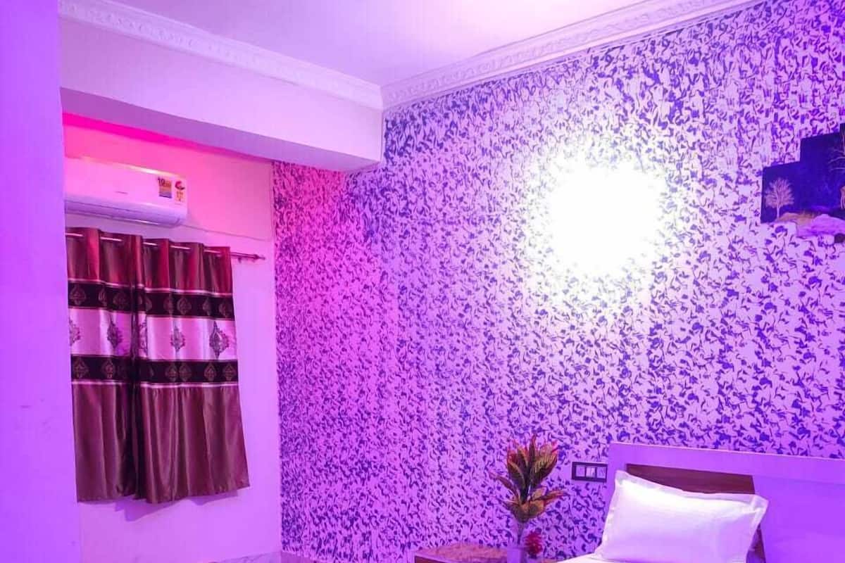 Un dormitorio con cama, mesita de noche y una pared con estampado floral.