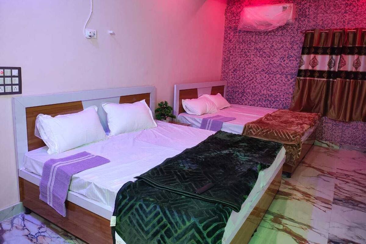 Habitación de hotel con dos camas, aire acondicionado de pared y un enchufe.