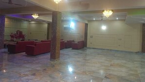 Un hall d’entrée spacieux, doté d’un sol en marbre, de sièges rouges et de lustres.
