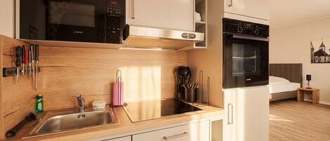 Una cocina moderna con horno empotrado, microondas y pileta.