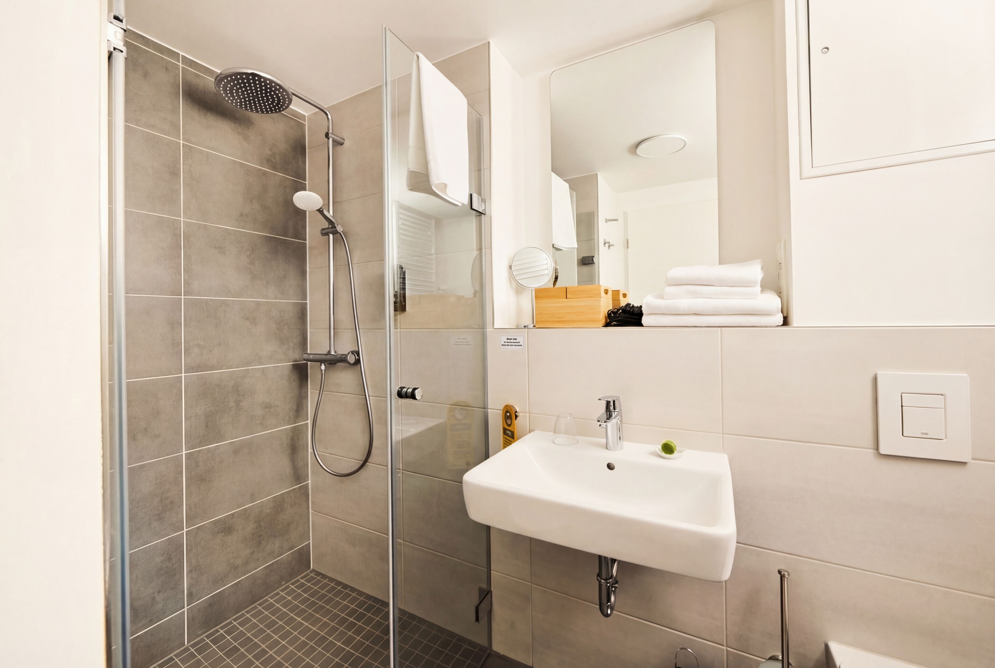A modern bathroom with a glass-enclosed shower, a white sink, and a mirror.