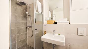 A modern bathroom with a glass-enclosed shower, a white sink, and a mirror.