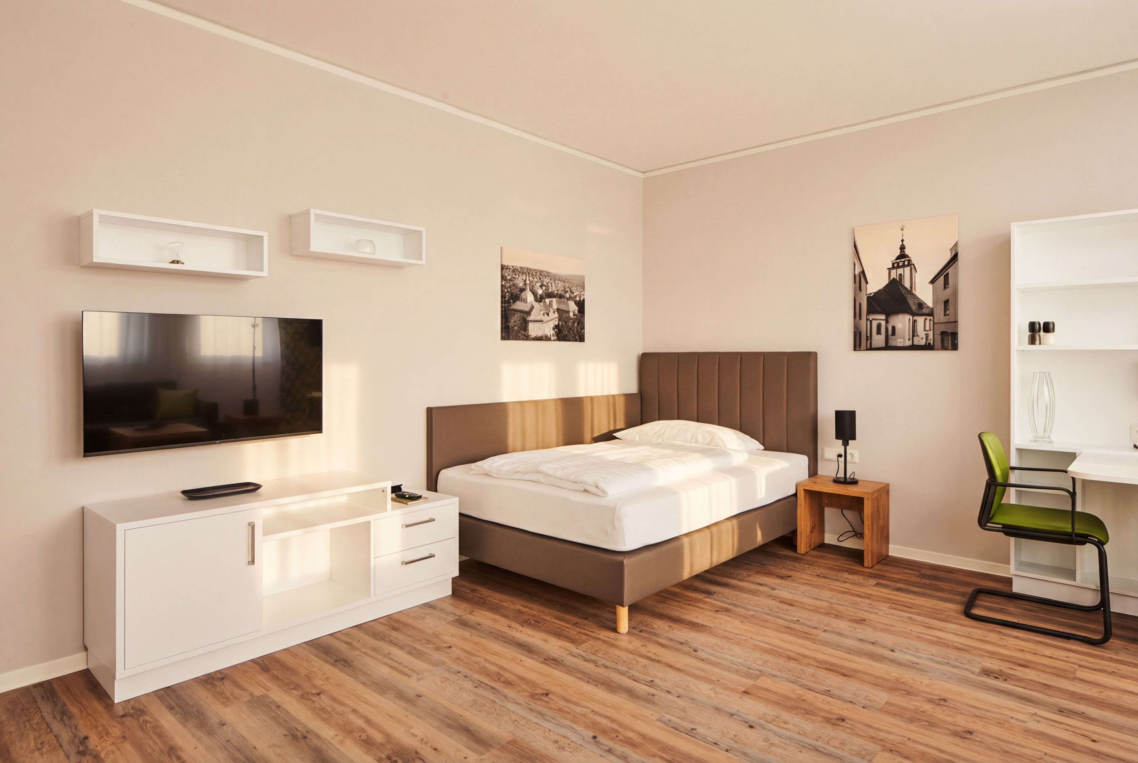 A modern bedroom with a bed, TV, bedside table, and a chair.