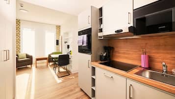 Eine moderne Küche mit Mikrowelle, Backofen und Spüle. Ein Essbereich mit Tisch und Stühlen ist ebenfalls vorhanden.