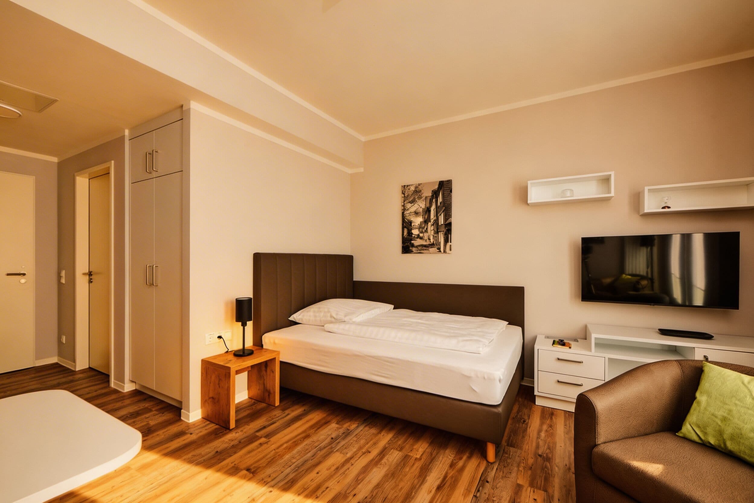 Un dormitorio moderno con cama, televisor, escritorio y sofá.