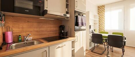 Una cucina moderna con piano di lavoro in legno, lavello in acciaio inossidabile e forno a microonde integrato. C'è un'area pranzo con tavolo e sedie.