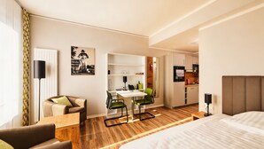 A hotel room with a bed, a desk with chairs, a kitchenette, and a bathroom. - ADAPT APARTMENT HOTEL Siegen (Siegen)