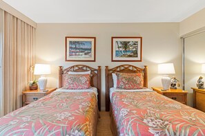 Une chambre d’hôtel avec deux lits simples, un grand miroir et deux tableaux encadrés accrochés au mur.