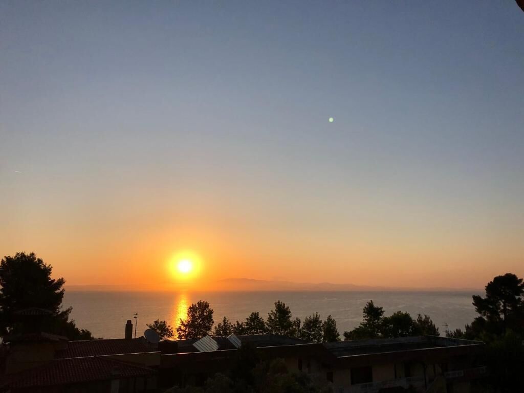 A sunset over a coastal area with buildings in the foreground.
