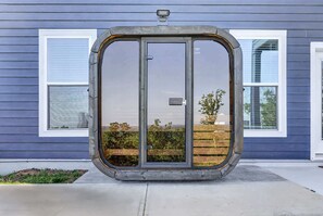 A house with a large sliding glass door, a small garden, and a view of the landscape.