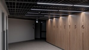A modern hallway with wooden lockers, a grid ceiling, and a light-colored floor. - RentPlanet - Studio Zwycięska (Wroclaw)