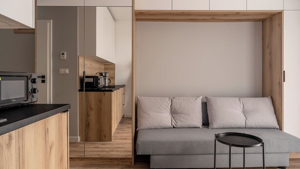 A modern kitchen with wooden cabinets and a built-in coffee machine. - RentPlanet - Studio Zwycięska (Wroclaw)